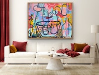 an abstract painting hangs above a couch in a living room