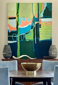 a dining room with blue chairs and an abstract painting