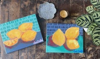 two paintings of lemons on a wooden table