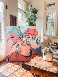 a living room with a painting of a potted plant